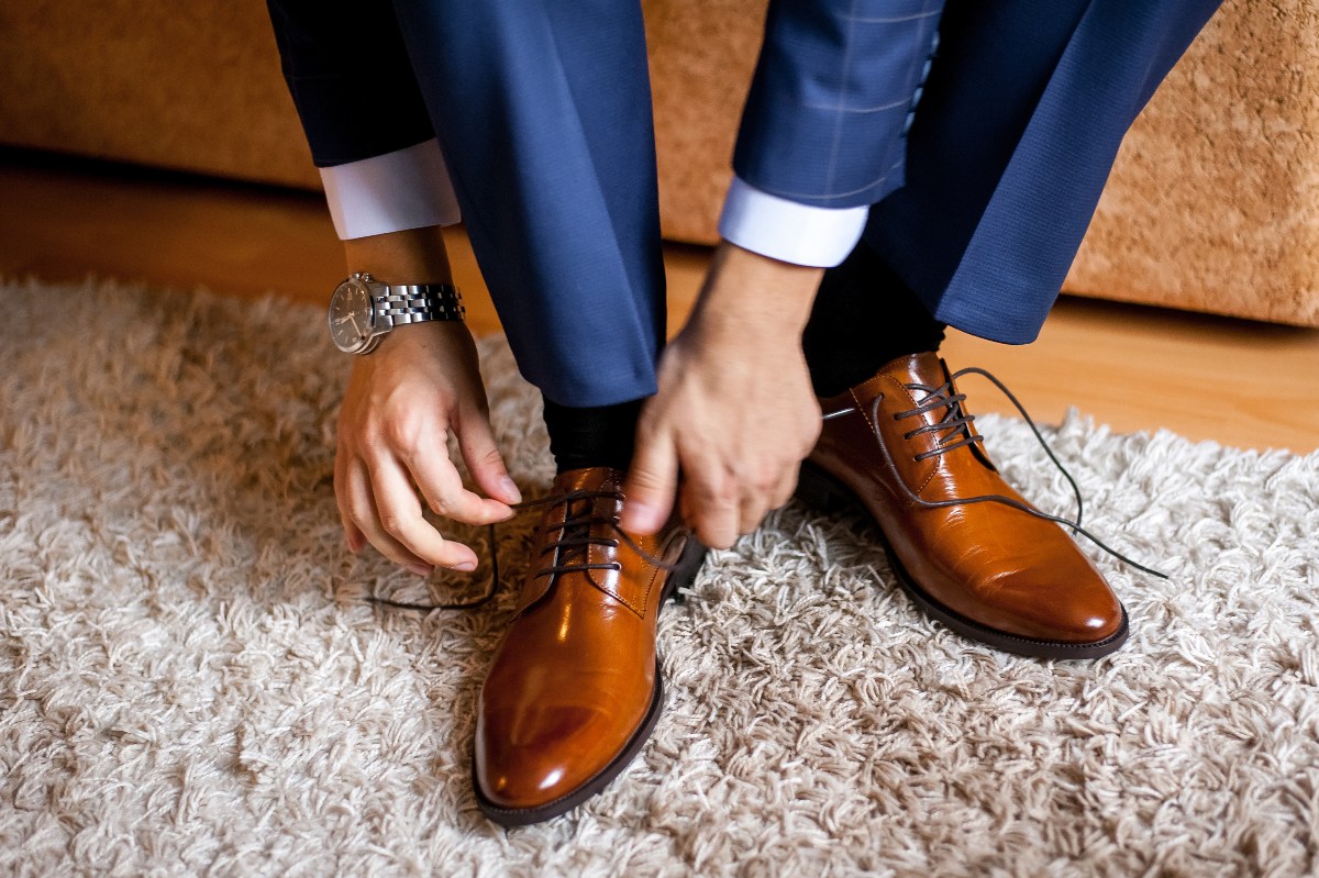 Beim Vorstellungsgespräch sollten Sie nur neuwertige und geputzte Schuhe tragen Ein Mann im Anzug schnürt seine frisch geputzten Lederschuhe