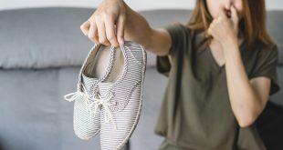 Junge Frau hält stinkende Schuhe von sich weg