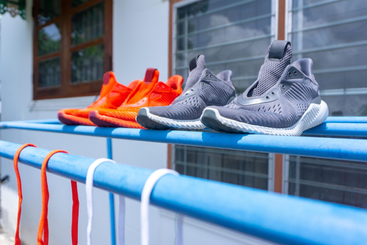 In den Trockner gehören Sneaker nicht - sie können darin Schaden nehmen Zwei Paar Schuhe (orange und grau) trocknen in der Sonne